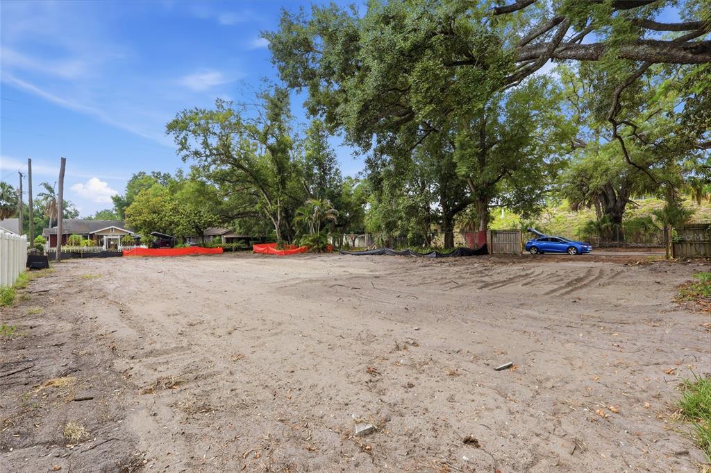 A vacant, sandy lot is bordered by mature trees and a residential neighborhood — 6201 E KING STREET, TAMPA, FL