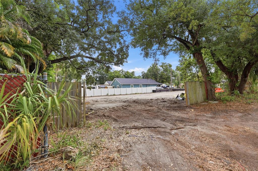 A dirt-covered vacant lot is framed by wooden fencing and large trees — 6201 E KING STREET, TAMPA, FL