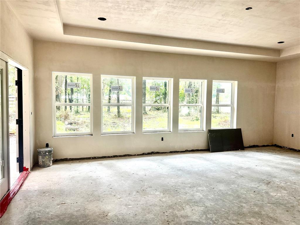 An unfinished room features five large windows, a tray ceiling, and bare concrete floors — 23161 NW 183RD LANE, HIGH SPRINGS, FL