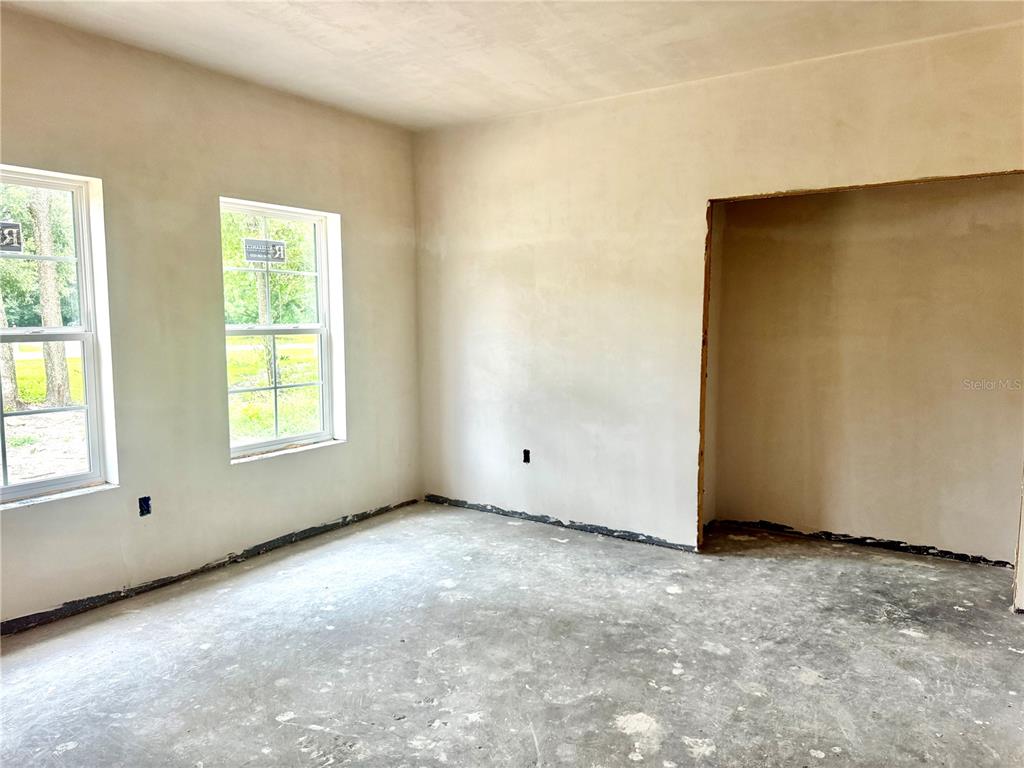 An unfinished room features bare plaster walls, two windows, and a concrete floor — 23161 NW 183RD LANE, HIGH SPRINGS, FL