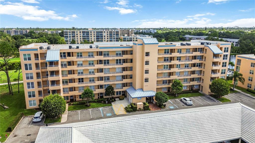 An aerial view of a multi-story, tan-colored apartment building with a parking lot — 4550 PINEBROOK CIRCLE UNIT 605, BRADENTON, FL