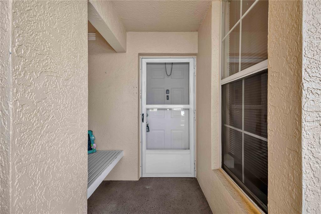 A covered entryway features a white storm door, a window, and a small bench — 4550 PINEBROOK CIRCLE UNIT 605, BRADENTON, FL