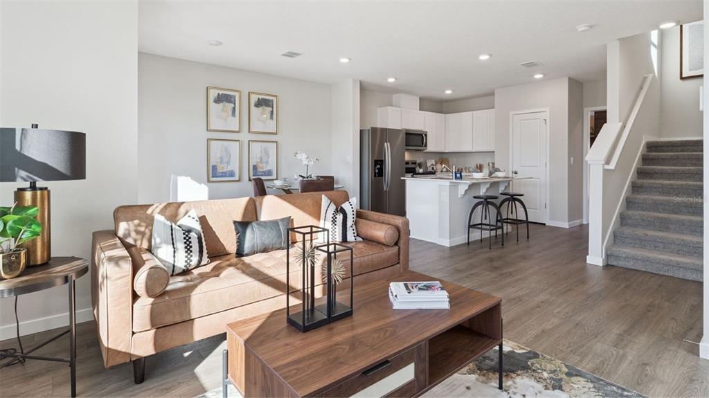 A living room with a leather sofa and coffee table opens to a kitchen area — 596 PRESTON COVE DRIVE, ST CLOUD, FL