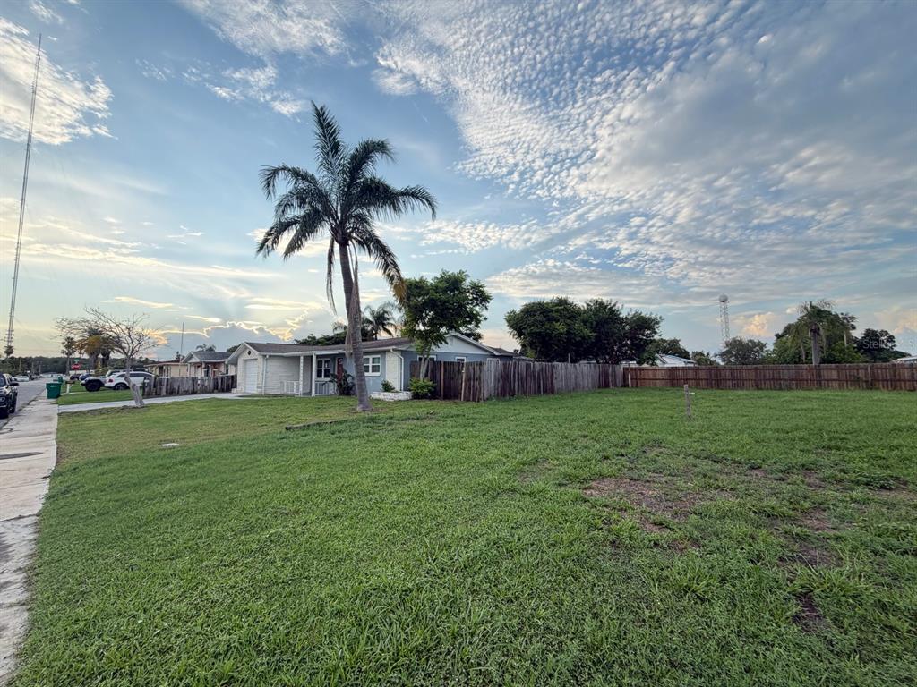 A grassy vacant lot sits next to a single-story house with a palm tree — 3221 ROXBURY DRIVE, HOLIDAY, FL