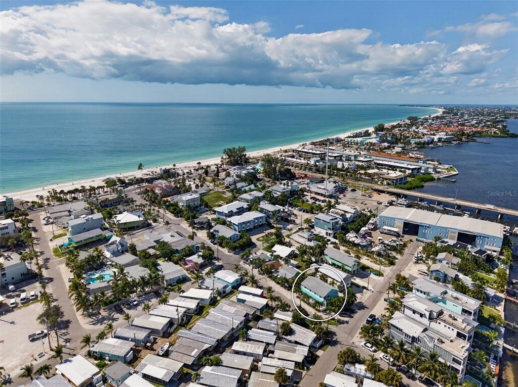 A two-story teal building features a red front door, a patio, and outdoor seating — 308 2ND STREET N UNIT 102, BRADENTON BEACH, FL