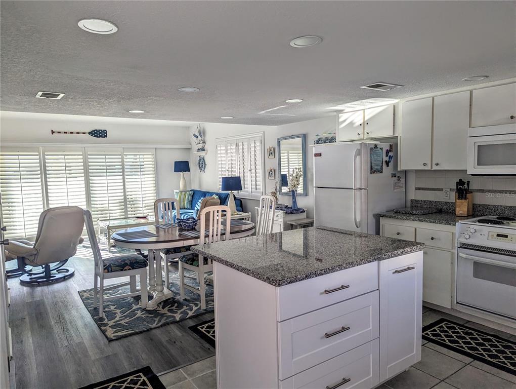 A kitchen with a granite-topped island opens into a dining area and living space — 815 OCEAN SHORE BOULEVARD UNIT 11A, ORMOND BEACH, FL