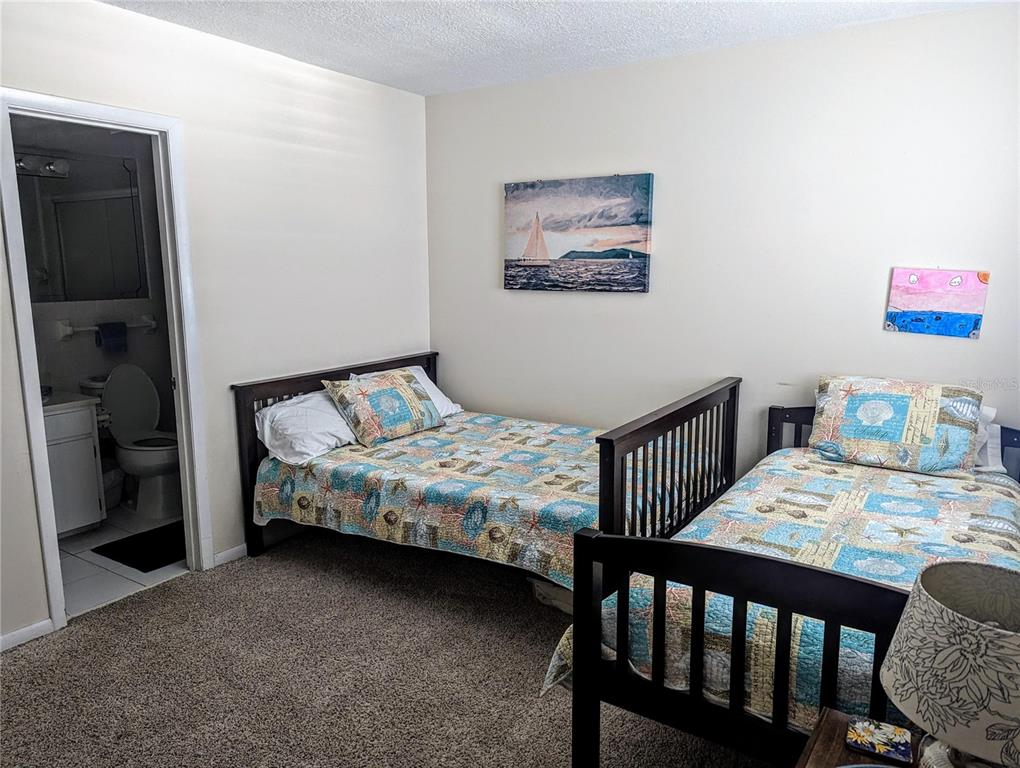 A bedroom with two twin beds, patterned quilts, and an attached bathroom — 815 OCEAN SHORE BOULEVARD UNIT 11A, ORMOND BEACH, FL