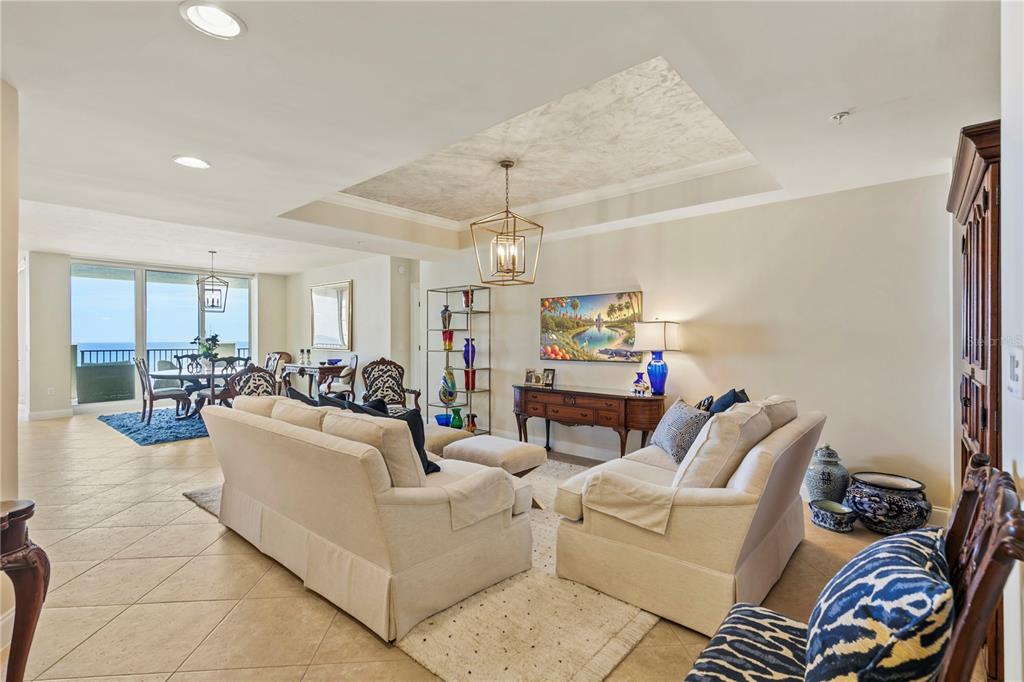 A living room with beige sofas, a tray ceiling, and a view of the ocean — 19 AVENUE DE LA MER UNIT 305, PALM COAST, FL