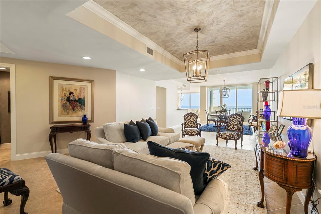 A living room with a tray ceiling, neutral furniture, and a view of the ocean — 19 AVENUE DE LA MER UNIT 305, PALM COAST, FL