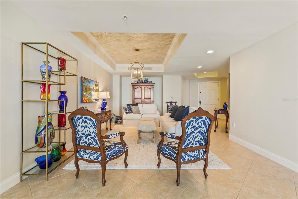 A living room features two patterned armchairs, a white sofa, and a gold metal shelving unit — 19 AVENUE DE LA MER UNIT 305, PALM COAST, FL