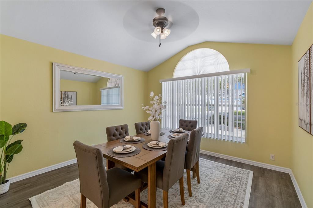 A bright entryway features light yellow walls, wood-look flooring, a white front door, and a chandelier — 12728 FLAMINGO PARKWAY, SPRING HILL, FL