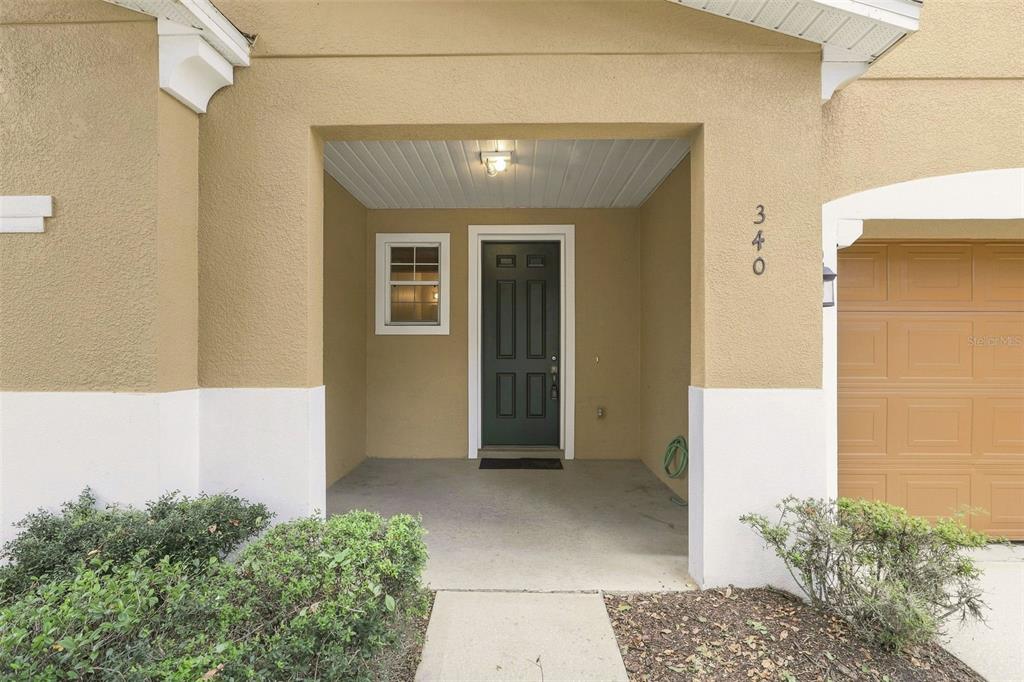 The exterior view shows a covered entryway with a dark door and a garage — 340 GOLDEN DEWDROP WAY, OVIEDO, FL