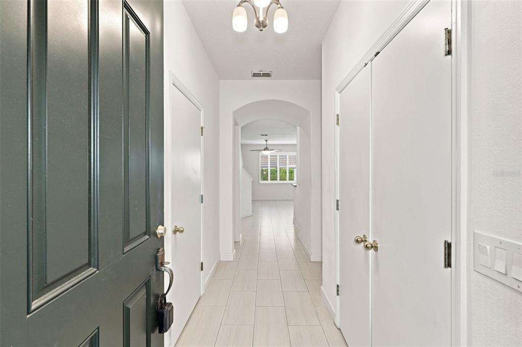 A bright entryway features white walls, tiled flooring, and a dark front door — 340 GOLDEN DEWDROP WAY, OVIEDO, FL