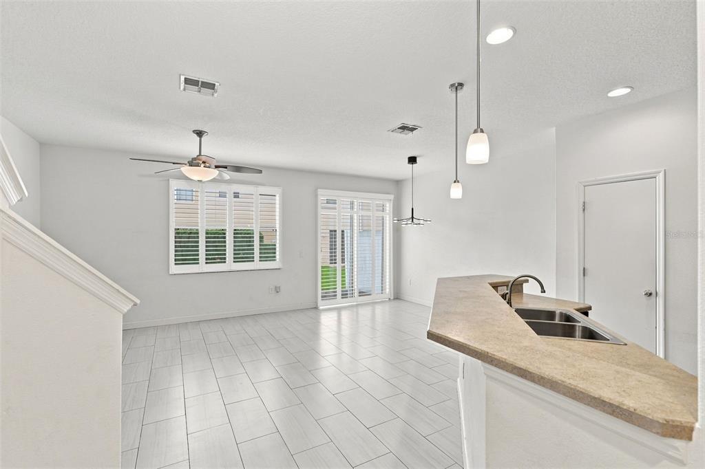 An open-concept kitchen and living area features light tile flooring and a breakfast bar — 340 GOLDEN DEWDROP WAY, OVIEDO, FL