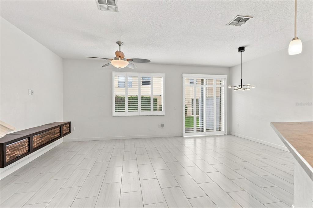 A bright living room features white tile floors, a ceiling fan, and sliding glass doors — 340 GOLDEN DEWDROP WAY, OVIEDO, FL