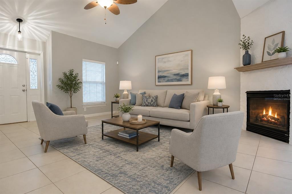 A living room features a vaulted ceiling, a fireplace, tile flooring, and neutral furniture — 183 HIGHLAND ROAD, TARPON SPRINGS, FL