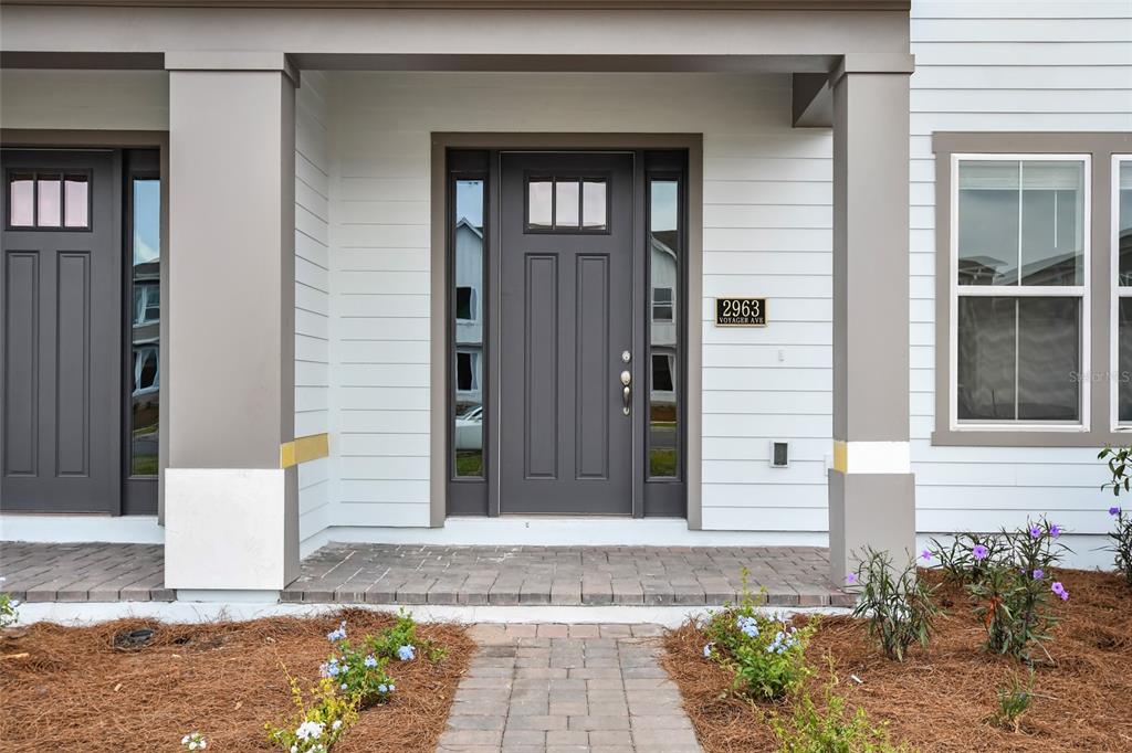 A gray front door with sidelights and a brick walkway under a covered porch — 2963 VOYAGER AVENUE, ST CLOUD, FL