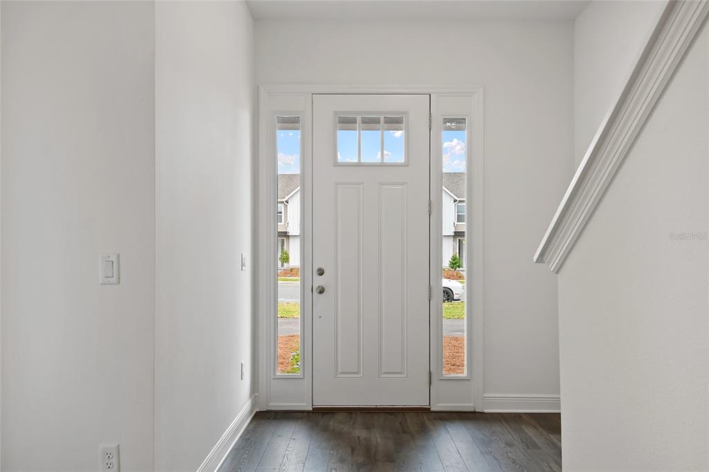 An entryway with a white front door, sidelights, and dark wood-look flooring — 2963 VOYAGER AVENUE, ST CLOUD, FL