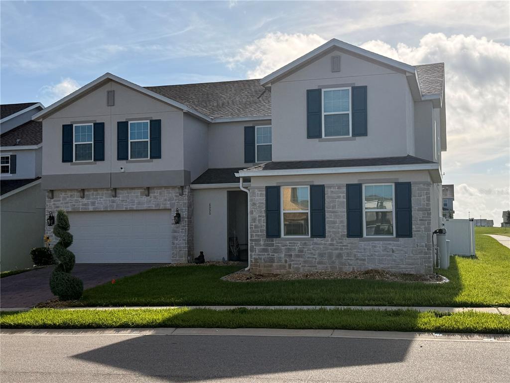 A two-story house with a stone facade, a two-car garage, and blue window shutters — 6990 ROLLING GARDENS LOOP, GROVELAND, FL