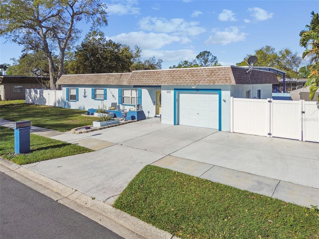 A single-story house with a blue exterior, a shingled roof, and a concrete driveway — 12252 ELDON DRIVE, LARGO, FL