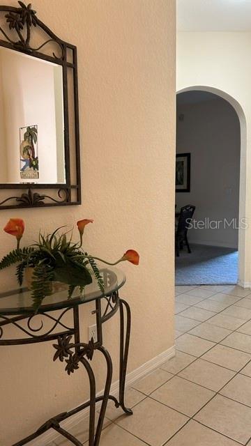 A metal console table with a plant and mirror sits in a tiled entryway — 3060 PIRATES RETREAT COURT UNIT 407, KISSIMMEE, FL