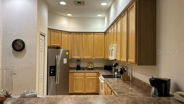 A kitchen features light wood cabinets, stainless steel appliances, and brown laminate countertops — 3060 PIRATES RETREAT COURT UNIT 407, KISSIMMEE, FL