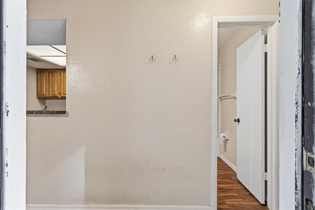 A beige wall with two coat hooks sits between a kitchen pass-through and a bathroom — 4705 SW 69TH TERRACE, GAINESVILLE, FL