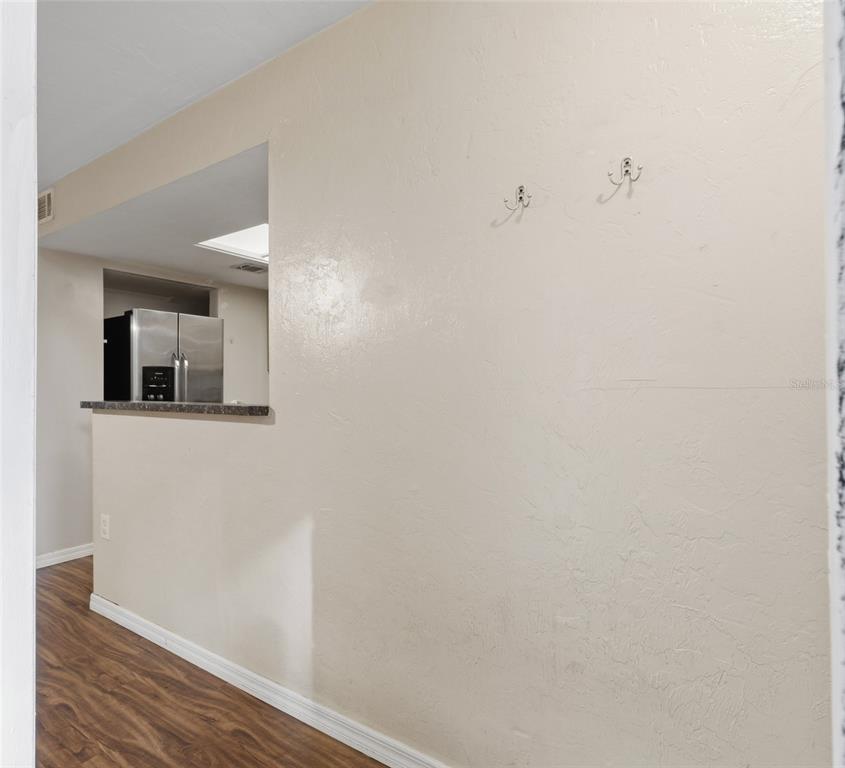 A view of a hallway wall with two hooks, looking into a kitchen with stainless appliances — 4705 SW 69TH TERRACE, GAINESVILLE, FL