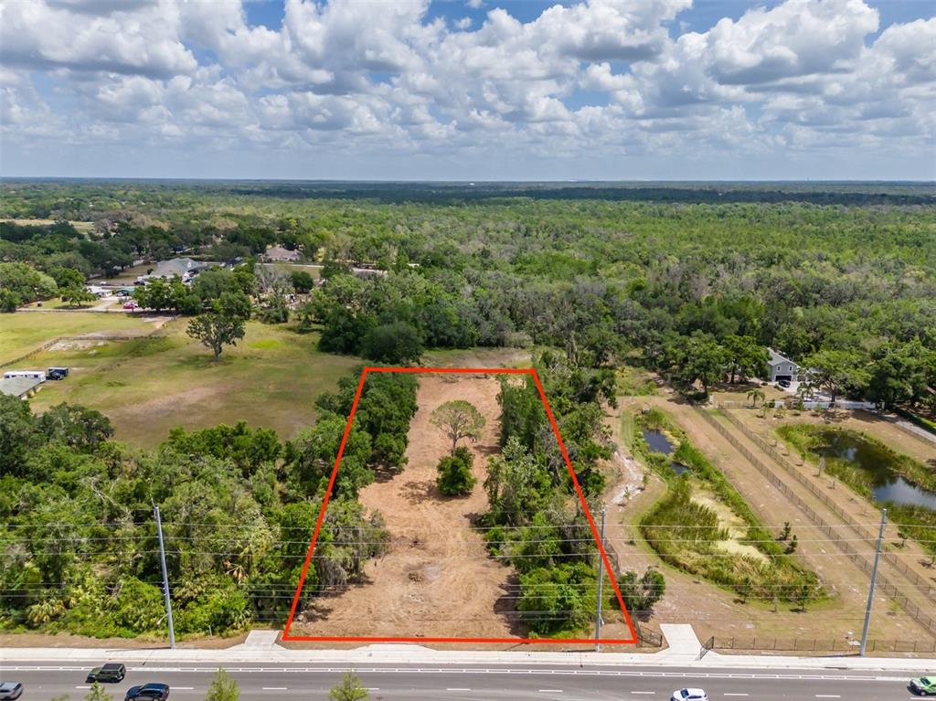 An aerial view shows a vacant, rectangular lot outlined in red along a paved road — 5106 BELL SHOALS ROAD, VALRICO, FL