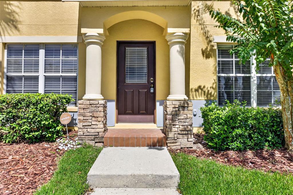 The front entrance features a dark door flanked by stone-based columns and two windows — 37602 AARALYN RD, ZEPHYRHILLS, FL