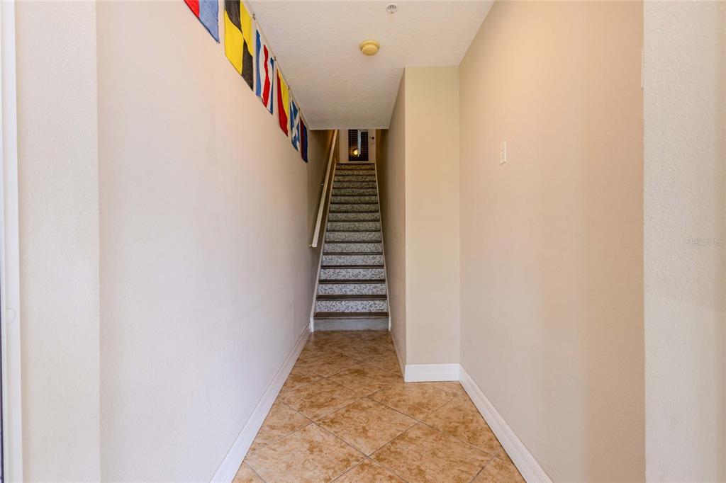 A tiled entryway leads to a carpeted staircase with a handrail and nautical flag decor — 3259 MANGROVE POINT DRIVE, RUSKIN, FL