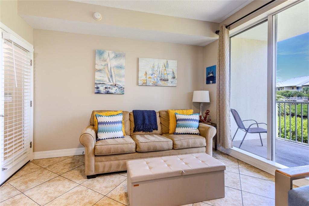 A living room features a beige sofa, a storage ottoman, and a sliding glass door — 3259 MANGROVE POINT DRIVE, RUSKIN, FL