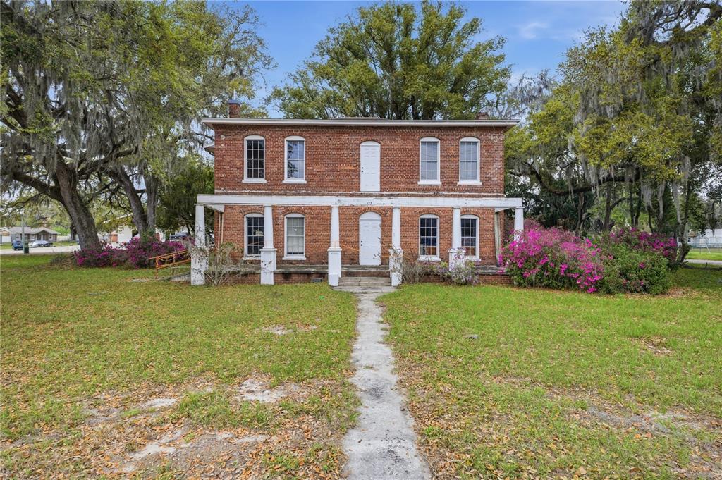 A two-story brick house with a front porch, white columns, and a central walkway — 120 N MAIN STREET, BUSHNELL, FL