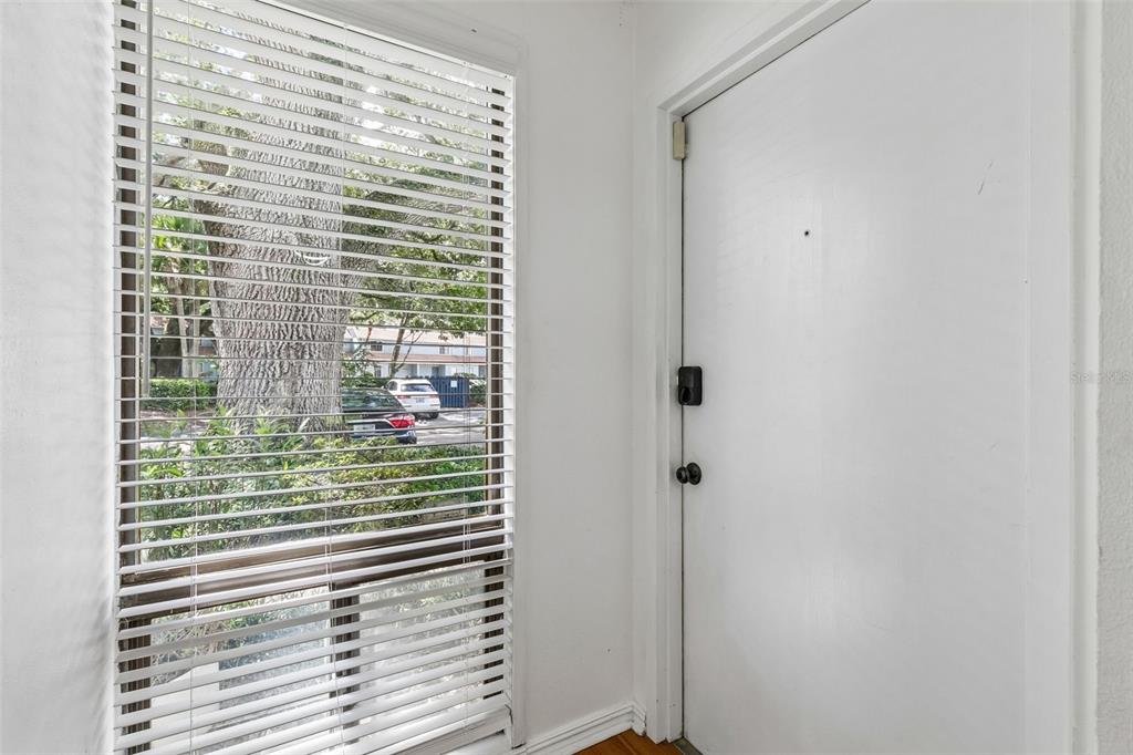 A white door with a smart lock stands next to a window with horizontal blinds — 70 MOREE LOOP UNIT 61, WINTER SPRINGS, FL