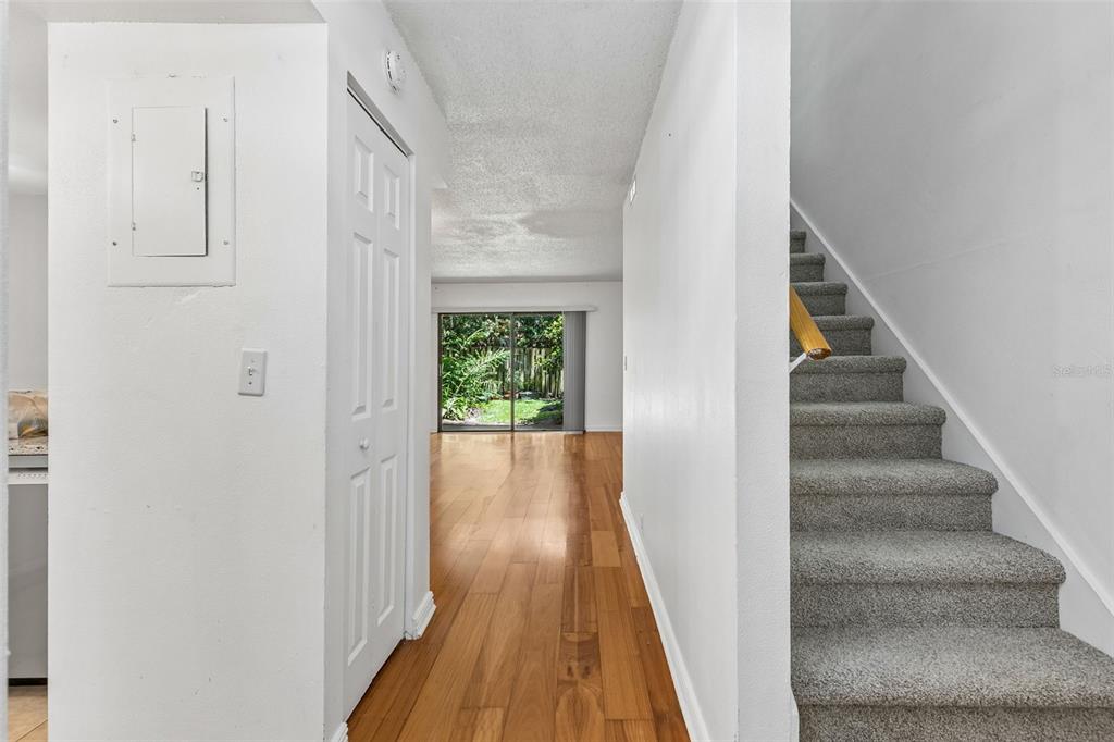 A hallway with wood flooring leads to a sliding glass door, with stairs on the right — 70 MOREE LOOP UNIT 61, WINTER SPRINGS, FL