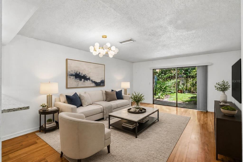 A living room features a sofa, armchair, coffee table, and sliding glass doors to a yard — 70 MOREE LOOP UNIT 61, WINTER SPRINGS, FL
