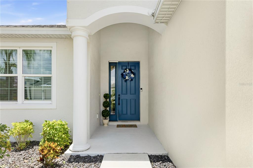 A blue front door with a side light sits under a covered entryway with a column — 12731 RAINWASHED LOOP, PARRISH, FL