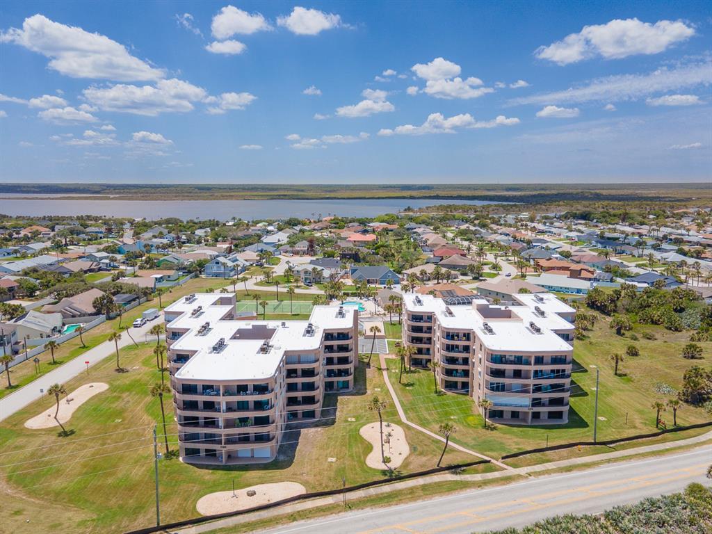 An aerial view shows two multi-story apartment buildings with flat roofs surrounded by green lawns — 3360 OCEAN SHORE BOULEVARD UNIT 3040, ORMOND BEACH, FL