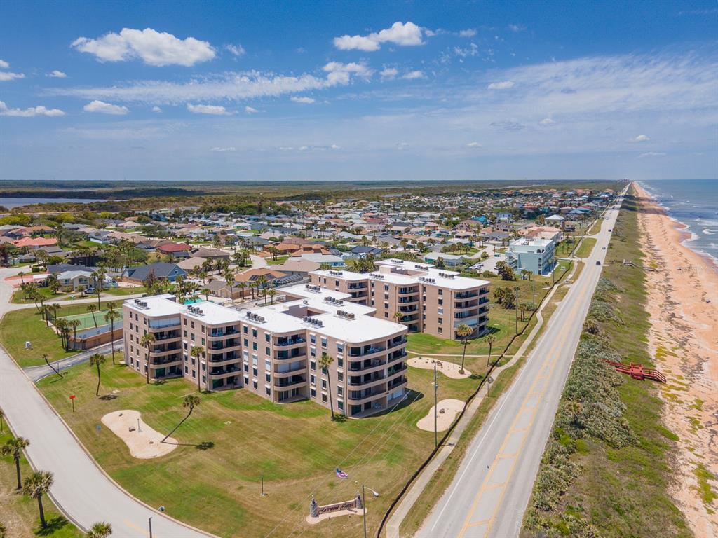 An aerial view shows a multi-story apartment complex situated between a coastal road and beach — 3360 OCEAN SHORE BOULEVARD UNIT 3040, ORMOND BEACH, FL