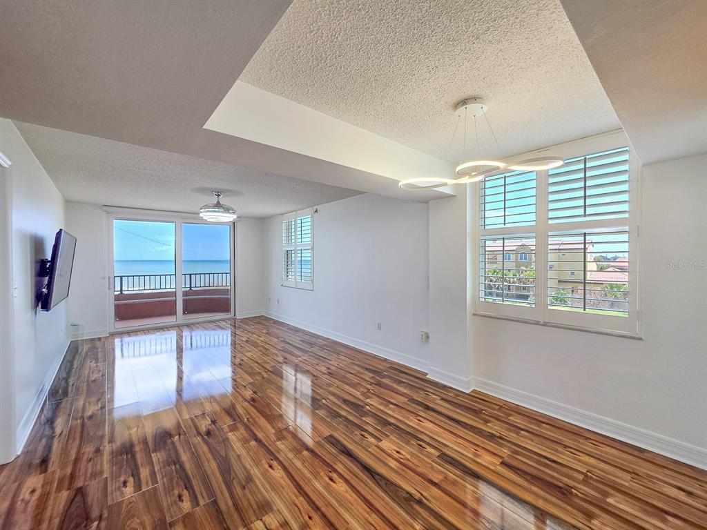 A living room with wood-look flooring, a ceiling fan, and a balcony overlooking the ocean — 3360 OCEAN SHORE BOULEVARD UNIT 3040, ORMOND BEACH, FL