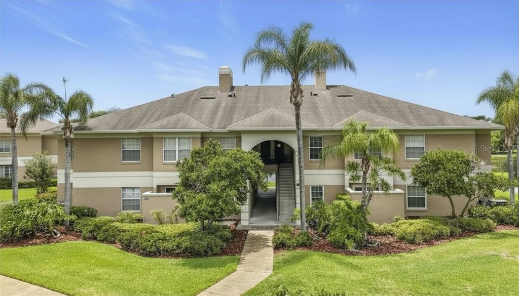 A two-story apartment building with tan stucco walls and a shingled roof at sunset — 704 EAGLE POND DRIVE UNIT 704, WINTER HAVEN, FL