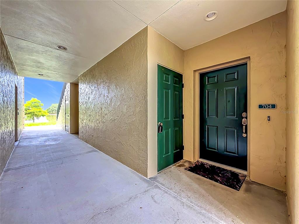 An exterior view of a building entrance with a dark green door numbered 704 — 704 EAGLE POND DRIVE UNIT 704, WINTER HAVEN, FL
