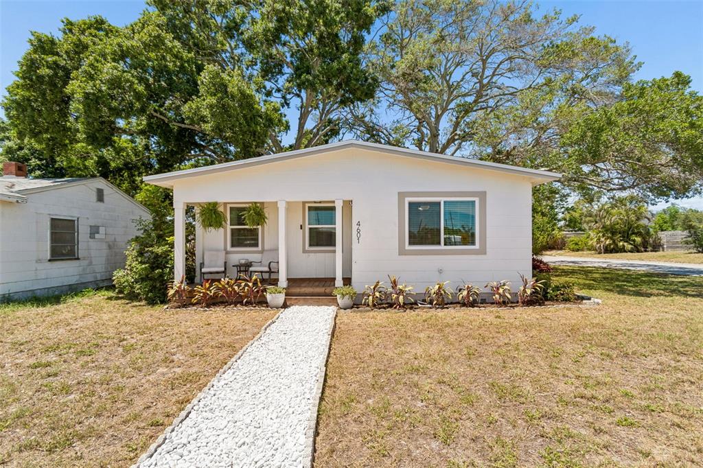 A small, white, single-story house features a covered front porch and a white gravel walkway — 4601 16TH AVENUE N, ST PETERSBURG, FL