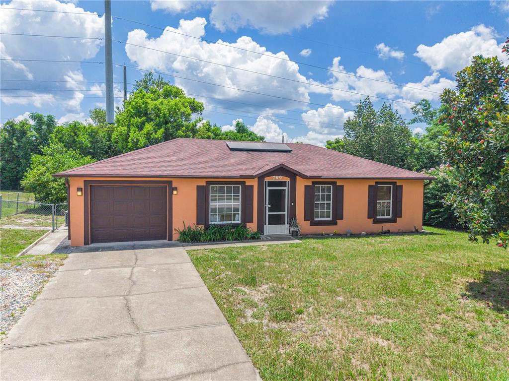A single-story house with an orange stucco exterior, brown shutters, and an attached garage — 769 TRUMBULL STREET, DELTONA, FL