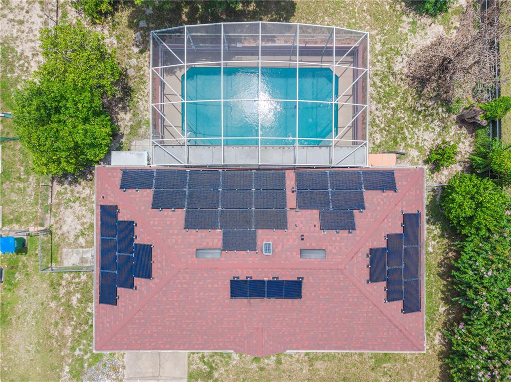 An aerial view shows a house roof with solar panels and an adjacent screened-in pool — 769 TRUMBULL STREET, DELTONA, FL