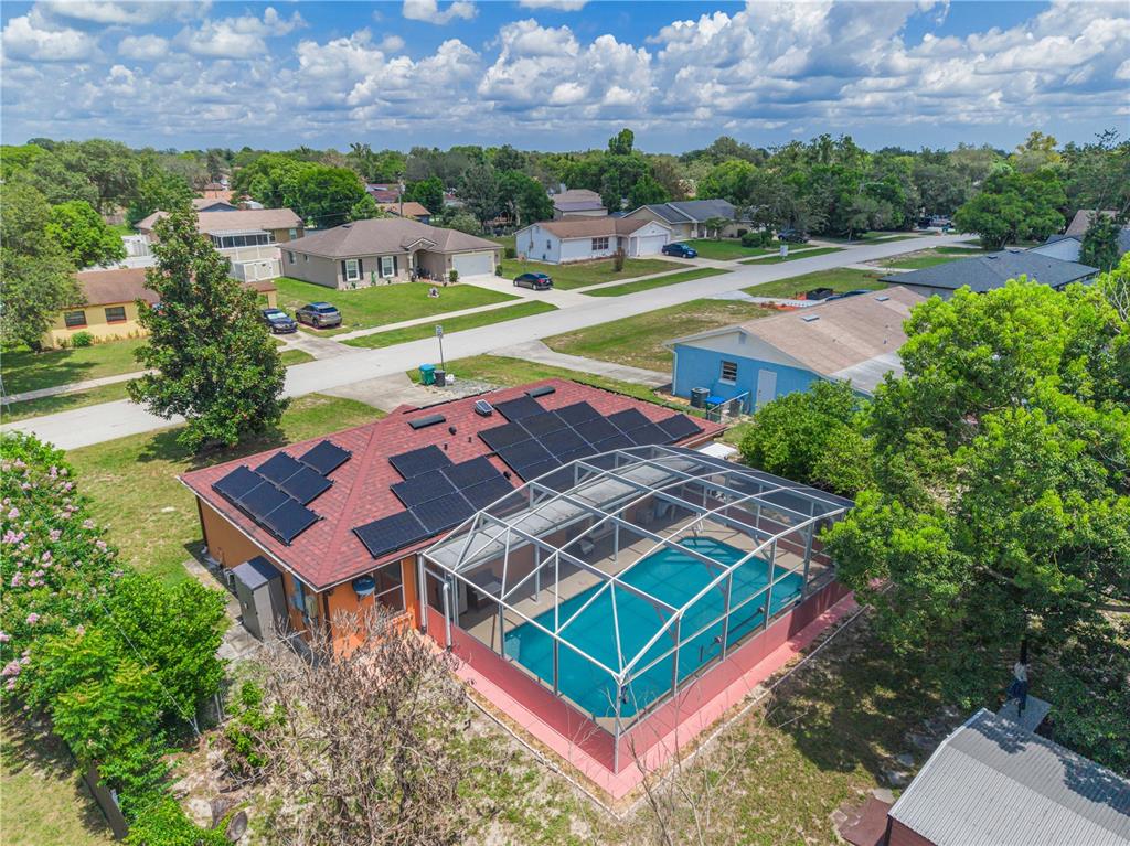 An aerial view of a house with a solar panel roof and a screened pool enclosure — 769 TRUMBULL STREET, DELTONA, FL