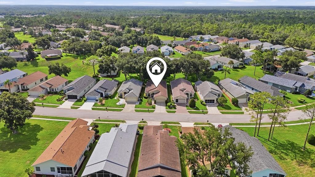 An aerial view shows a suburban neighborhood with houses, green lawns, and mature trees — 18114 BRELAND DRIVE, HUDSON, FL