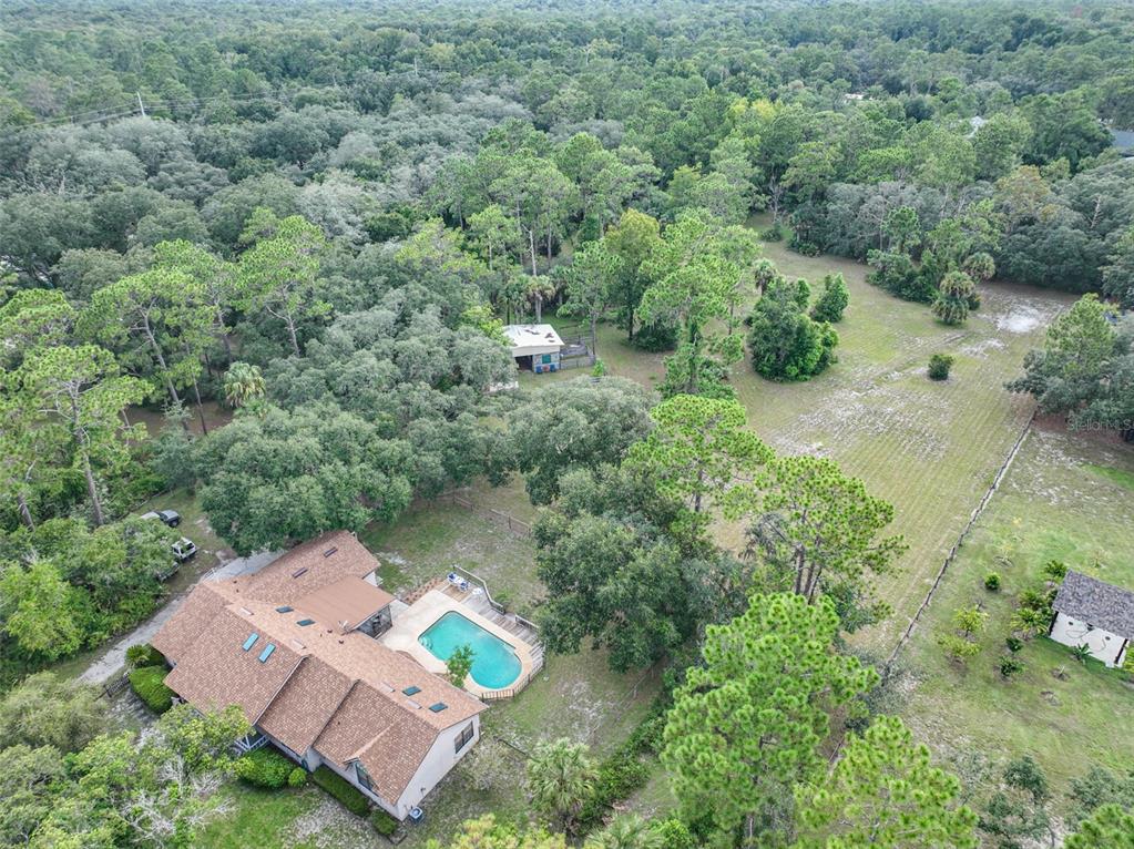 An aerial view shows a house with a pool, a detached shed, and surrounding woods — 2968 S TANNER ROAD, ORLANDO, FL