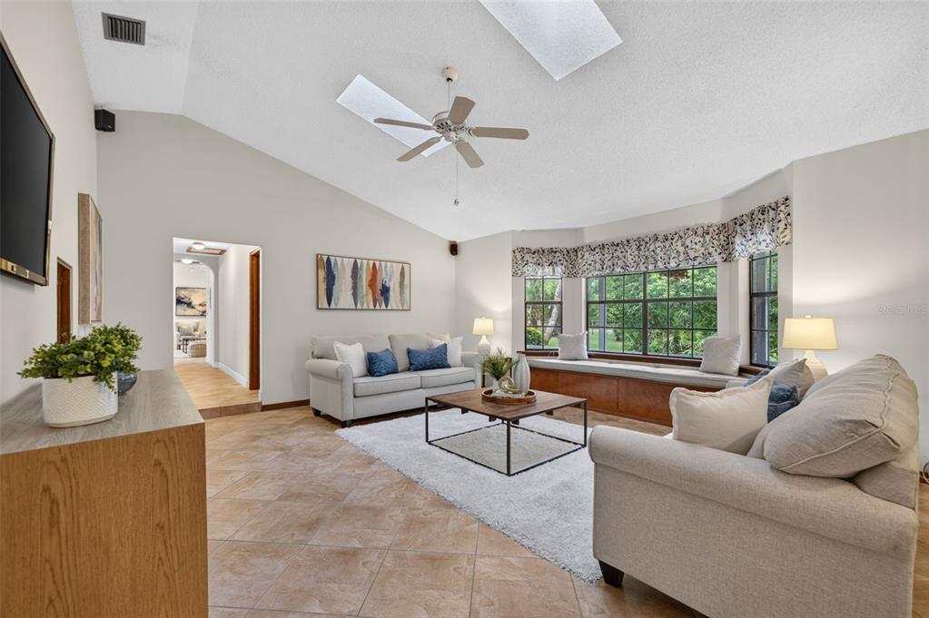 A living room with tile floors, a vaulted ceiling, a ceiling fan, and a bay window — 2968 S TANNER ROAD, ORLANDO, FL