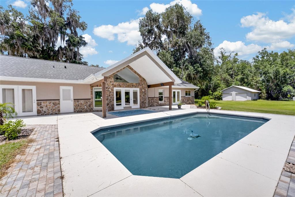 An aerial view of a house with a driveway and a pond on a wooded lot — 19785 NW 123RD COURT, MICANOPY, FL